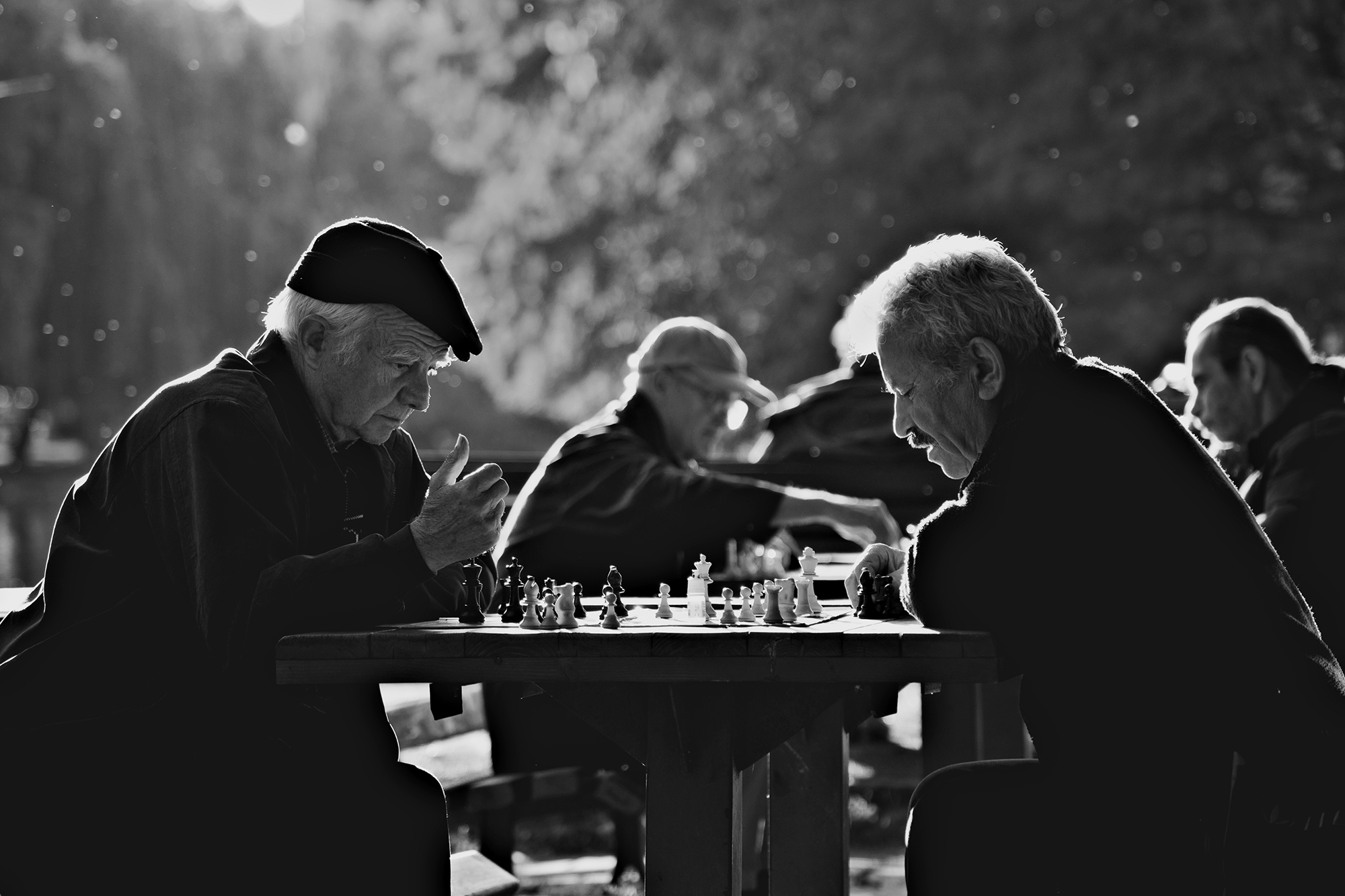 Black and white two men playing chess at outdoor table