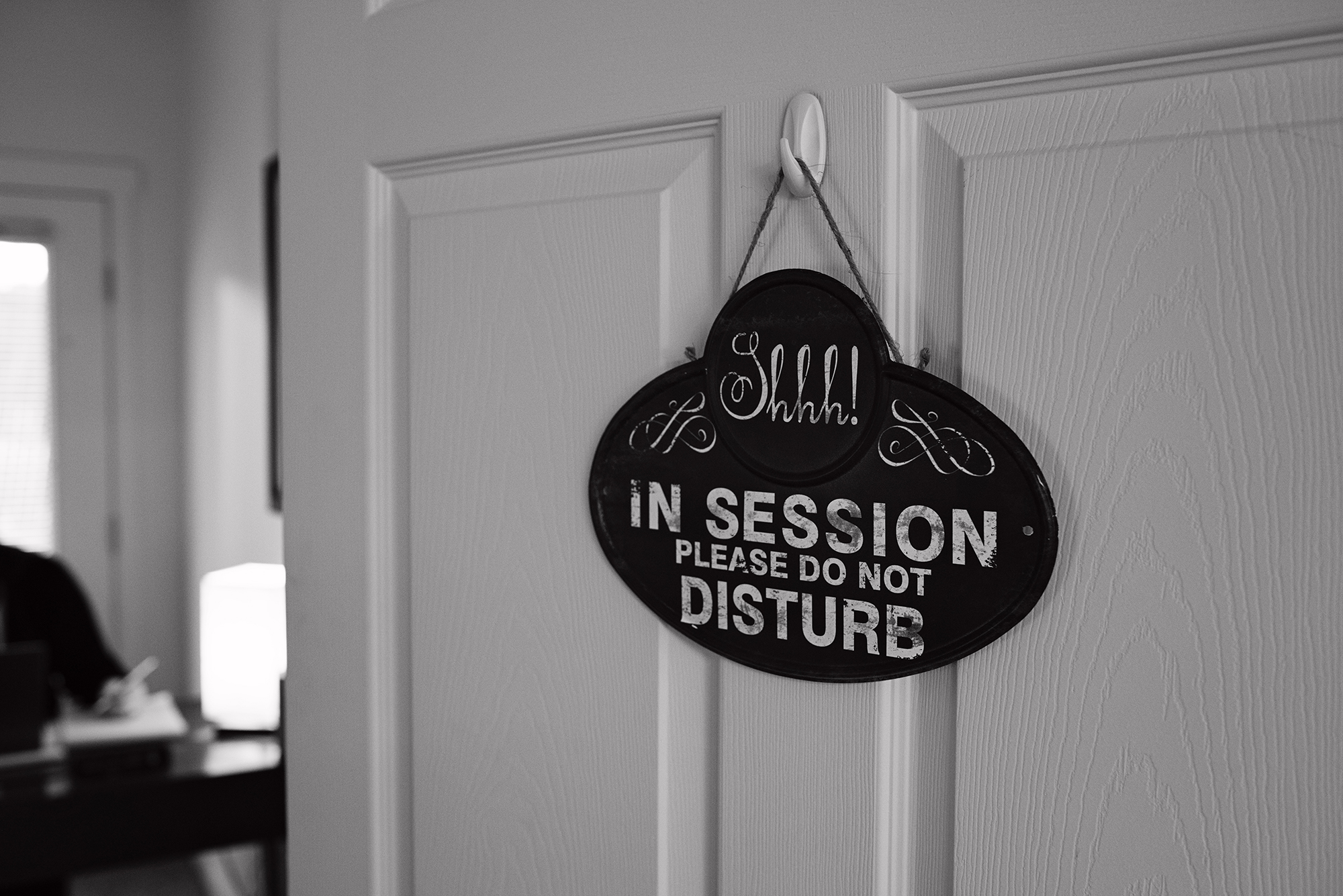 A partially closed door with Shhh In session Please do not disturb sign