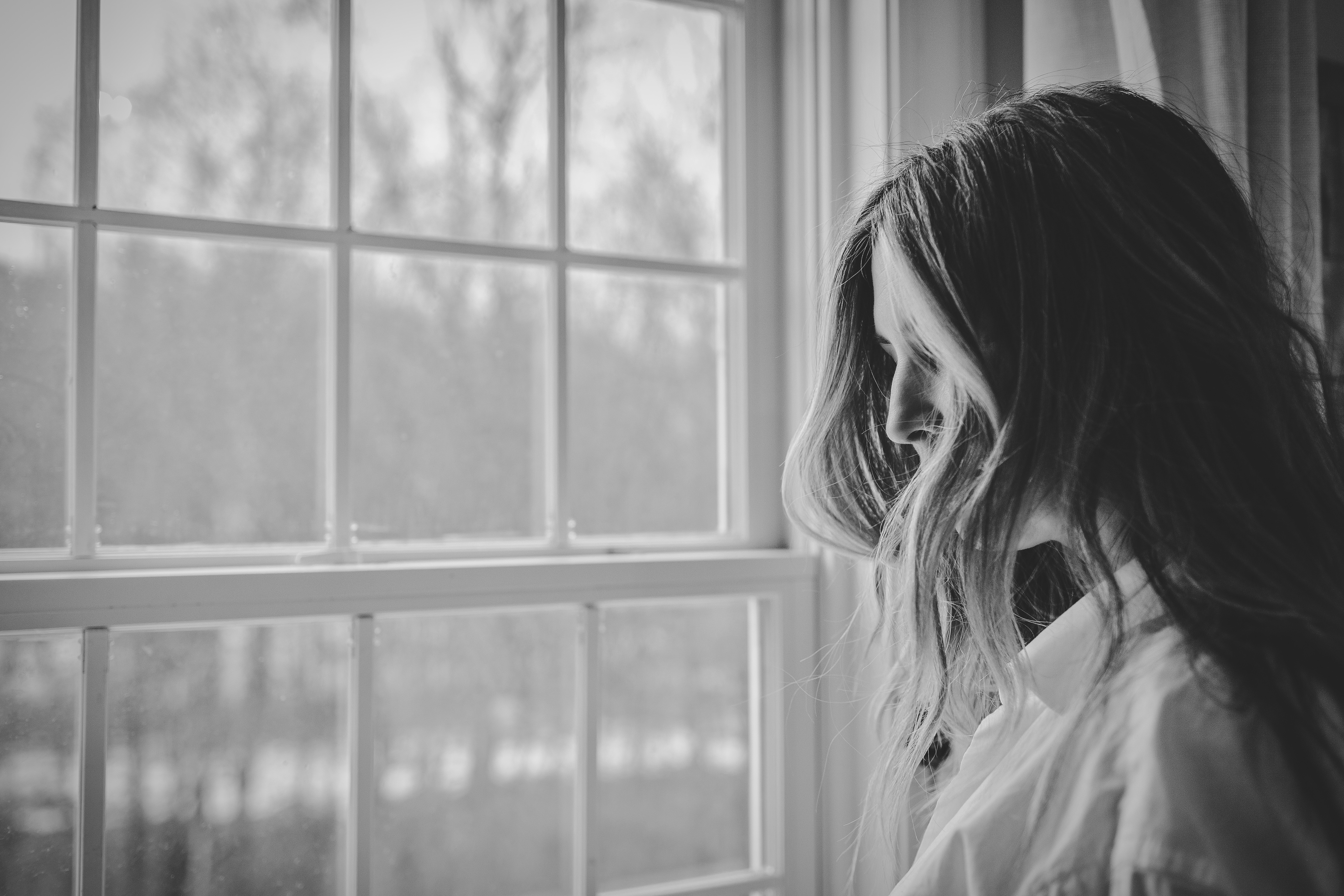 Side view of woman looking out of window in black and white